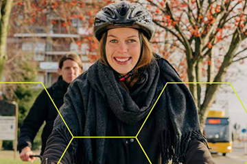 Kvinna med cykelhjälm ler mot kameran.